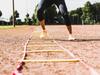 Young woman exercising on sports field with Fitness Town agility ladder